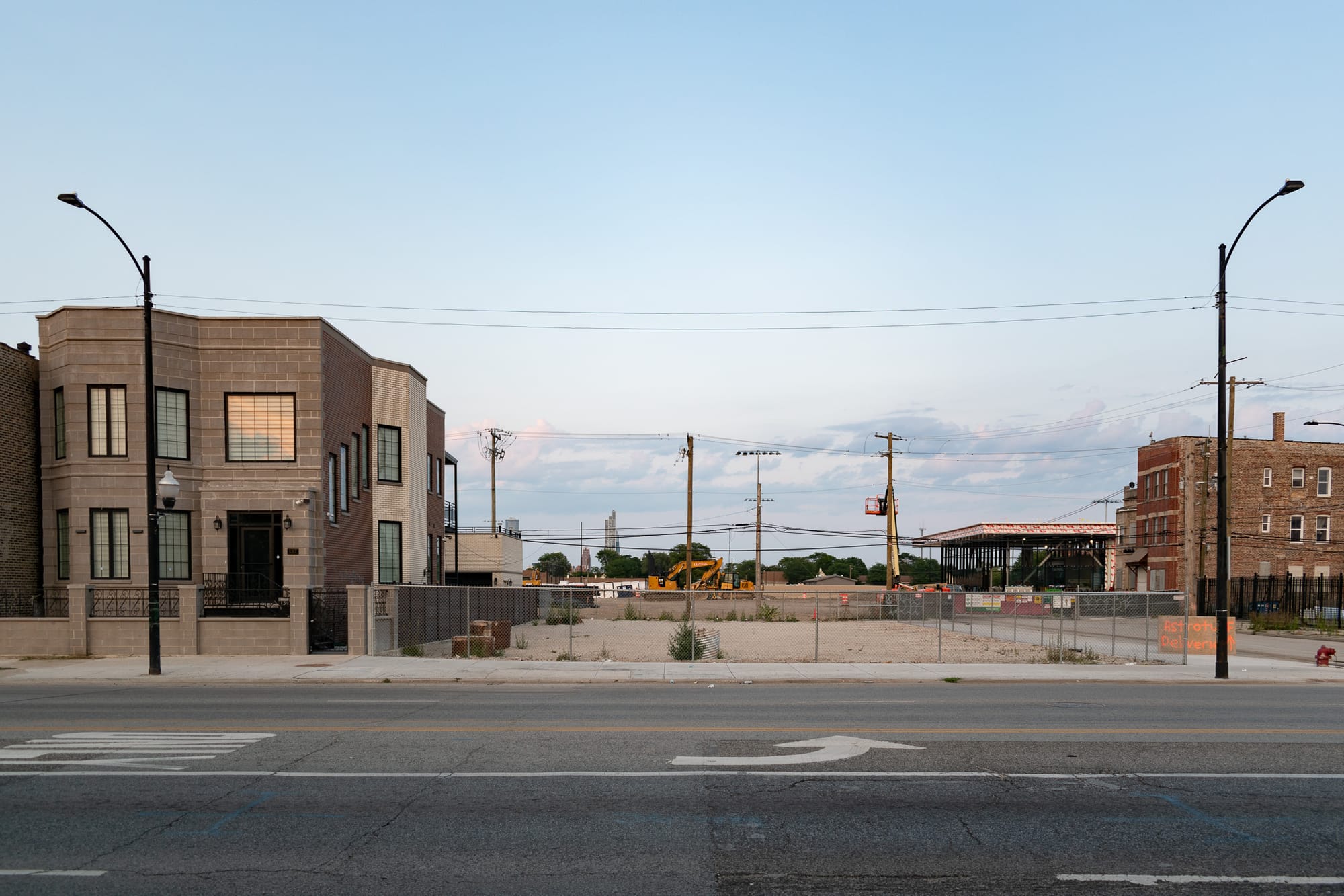 Gravel-covered vacant lot where the church once stood, the soccer training facility rising in the background 