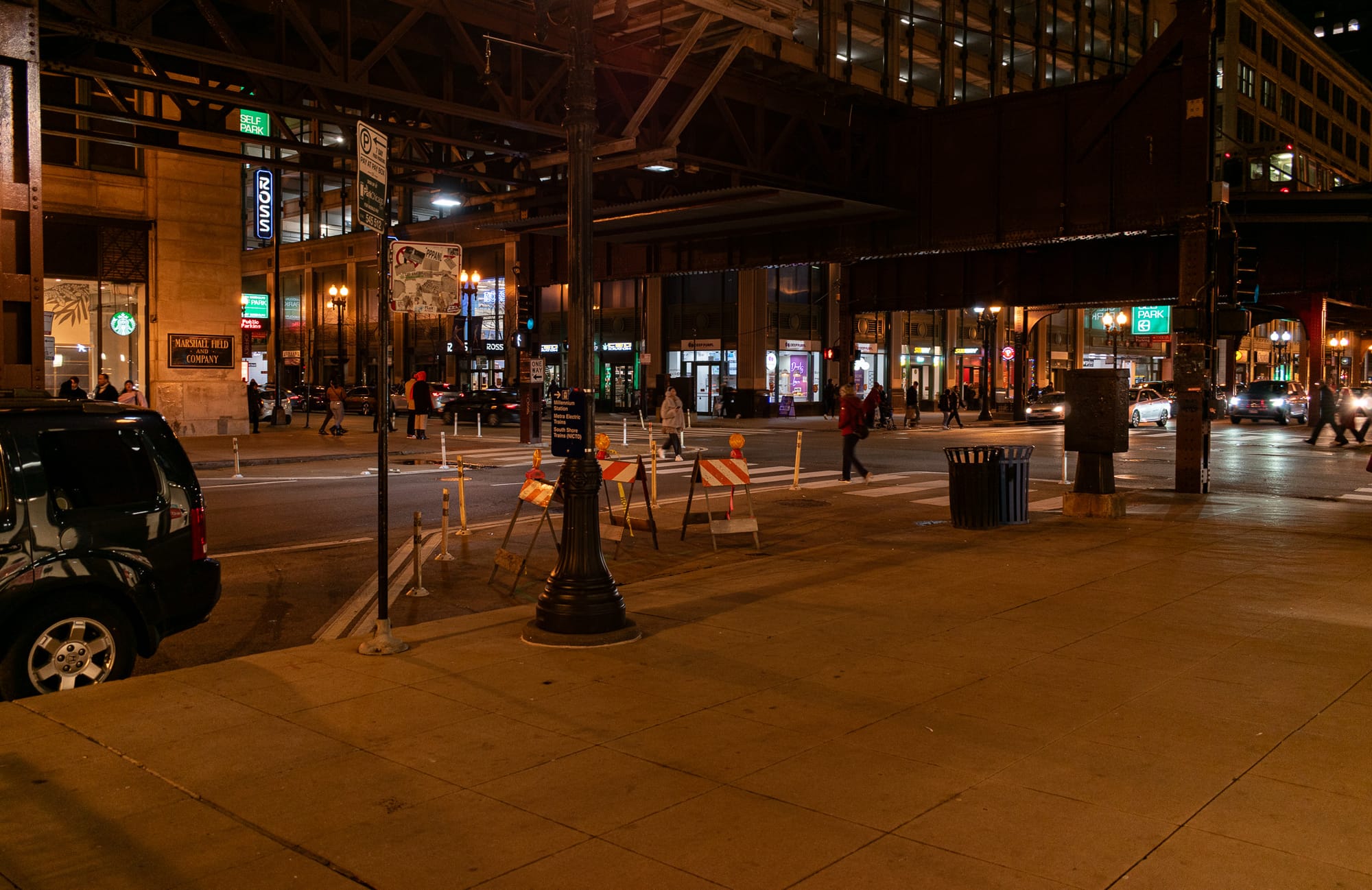 Facing the intersection of Wabash and Randolph at night, under the L superstructure, with pedestrians crossing the street.